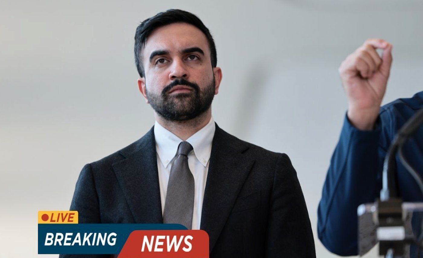 Man in suit and tie standing at a podium with a 'Breaking News' graphic overlay