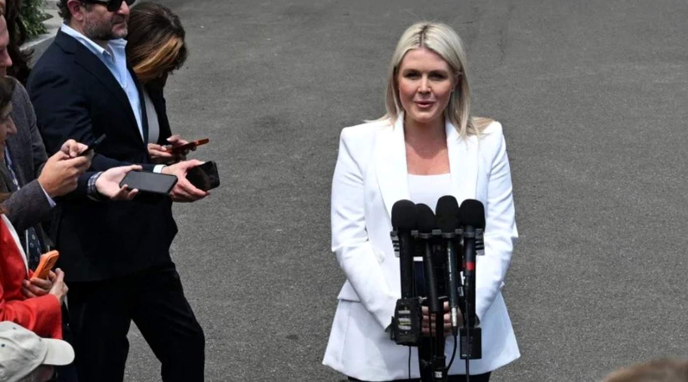 press briefing featuring a woman in a white suit at a podium