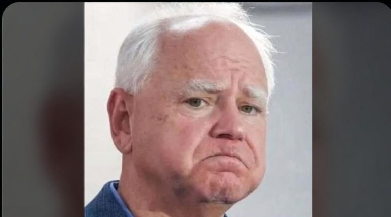 close-up portrait of white-haired man with serious expression wearing blue collared shirt