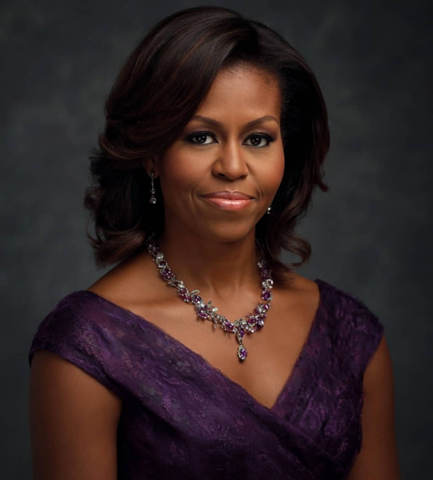michelle Obama wearing an elegant purple lace dress and ornate gemstone necklace poses