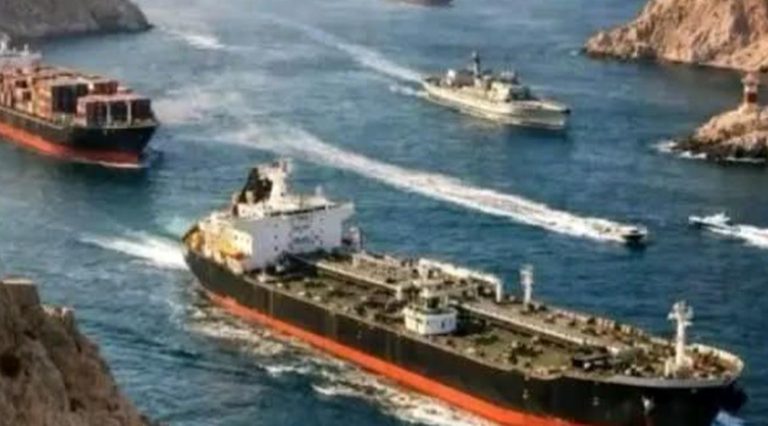 oil tanker and container ship escorted by naval vessel through narrow strait between