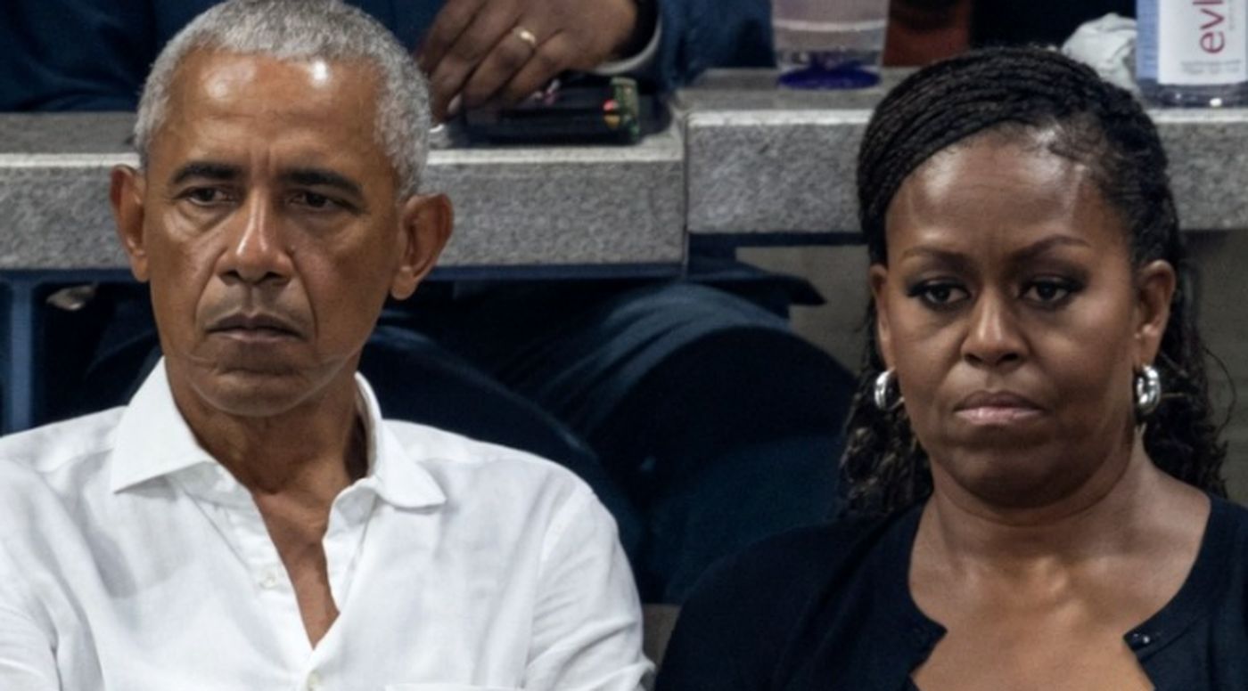 barack and Michelle Obama seated courtside with serious expressions at a basketball game