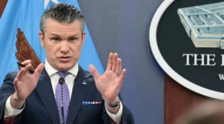 pete Hegseth gesturing with both hands at Pentagon podium with Department of Defense seal