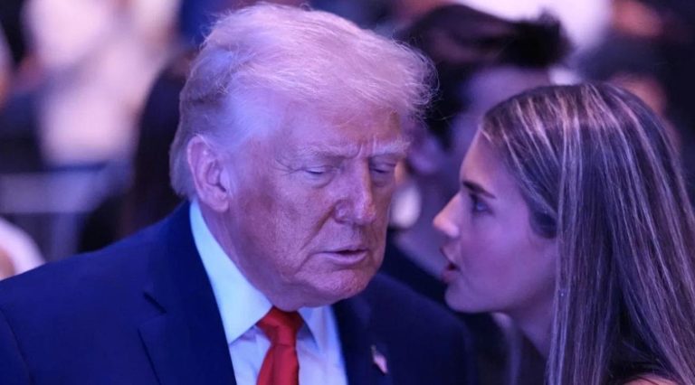 donald Trump in navy suit and red tie listens intently to a woman with long brown hair at