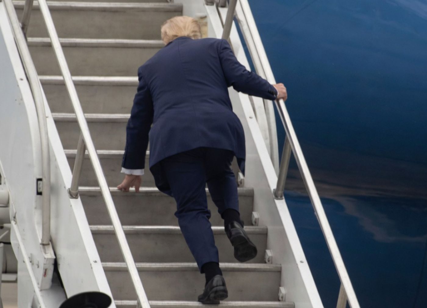donald Trump ascends stairs to board an airplane