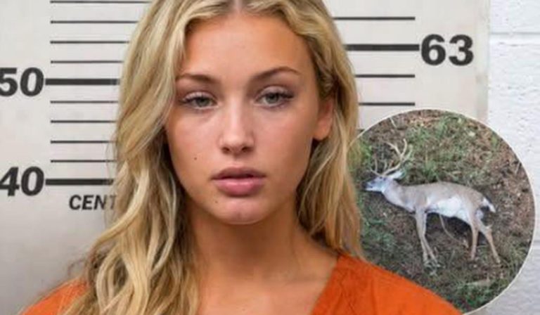 Blonde woman in orange jumpsuit with dead deer