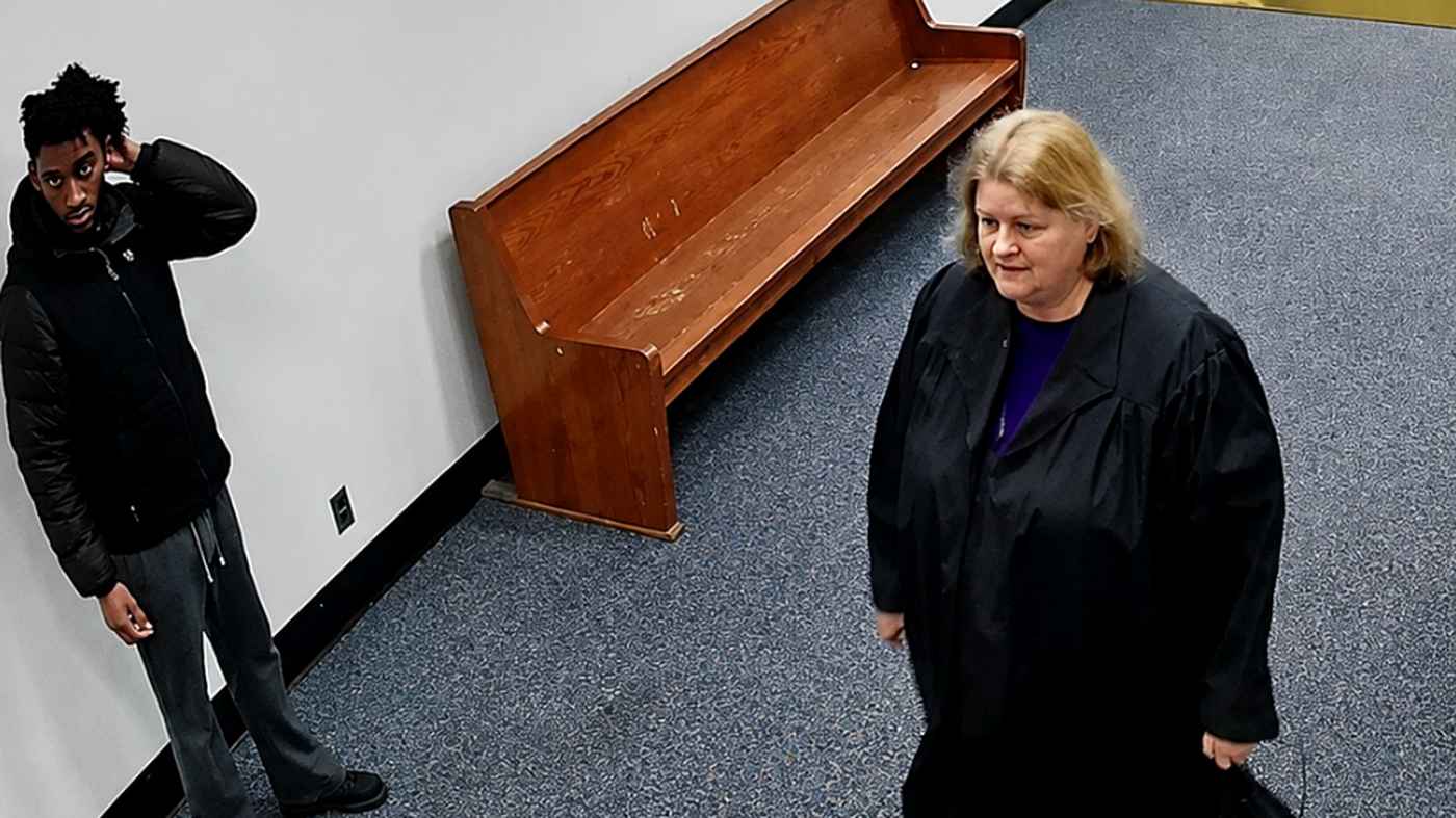 A judge in robes walking down a courtroom hallway.