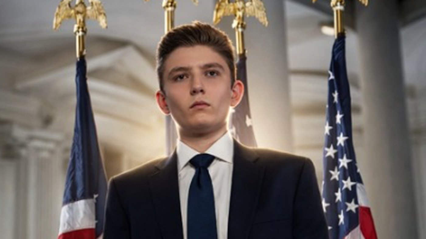 young man in suit stands confidently before American flags
