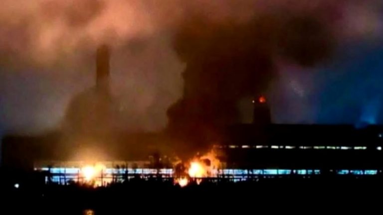 "Massive refinery fire with black smoke and orange flames"