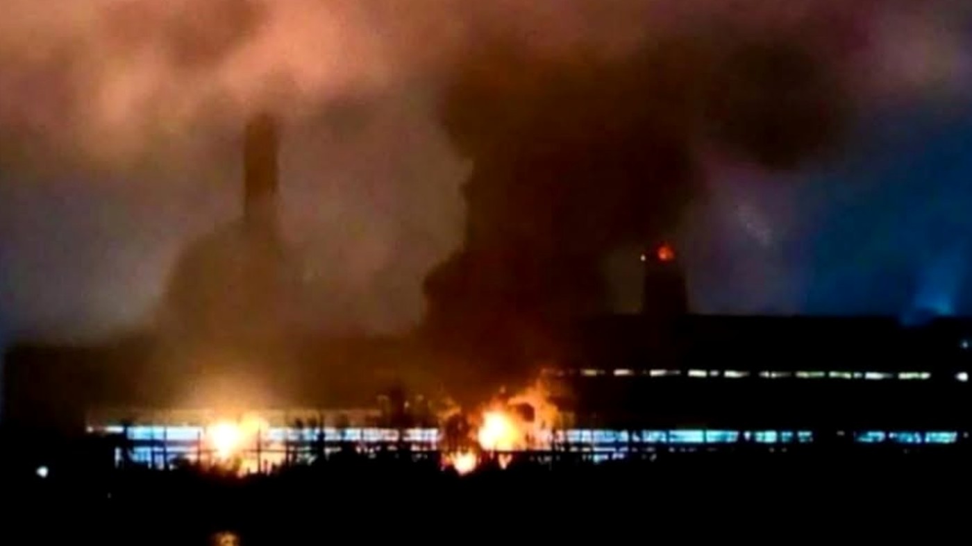 "Massive refinery fire with black smoke and orange flames"