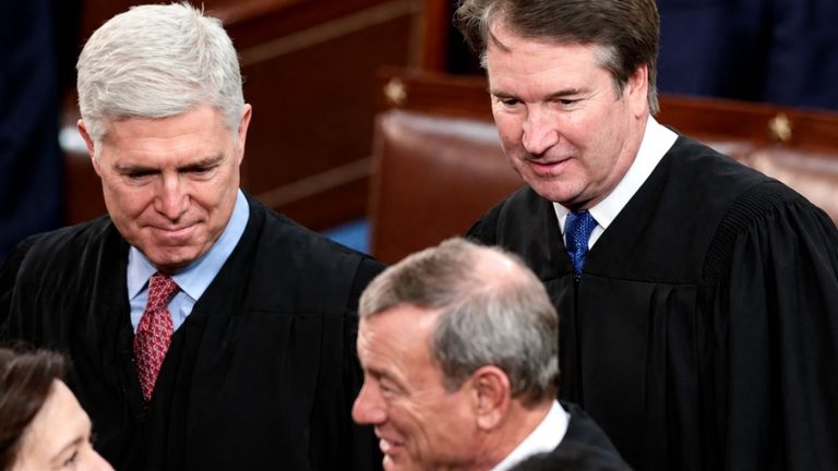 Neil Gorsuch and Brett Kavanaugh in judicial robes.