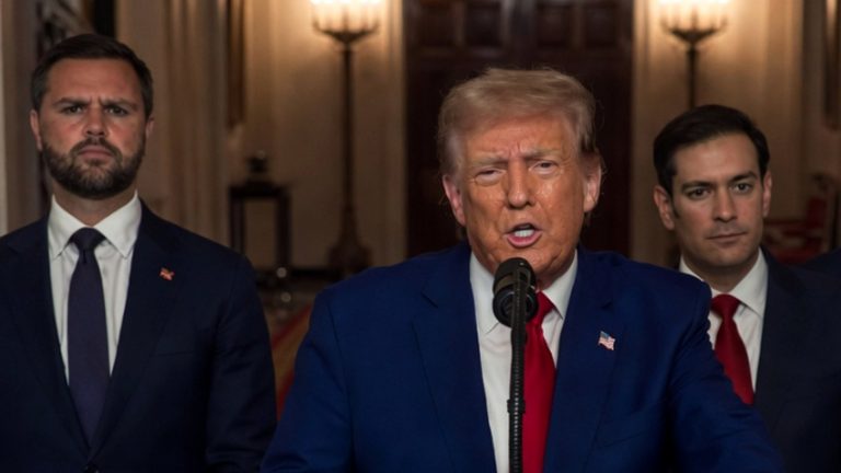 donald Trump speaks at a press conference with two aides