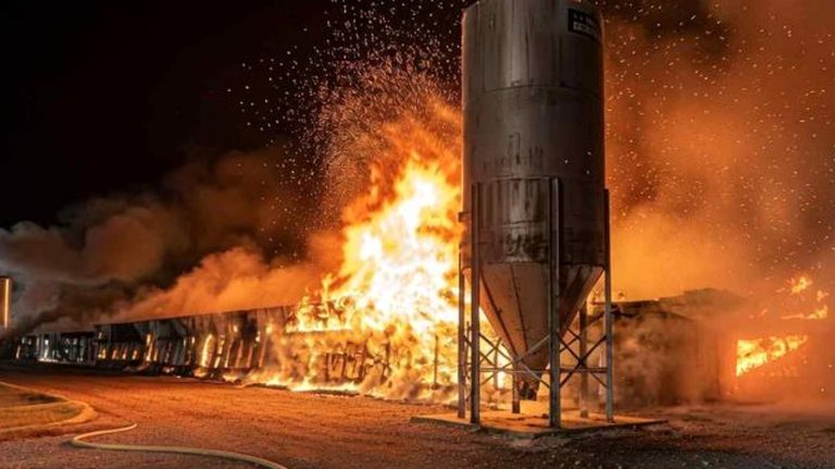 Massive fire engulfing a farm building at night.