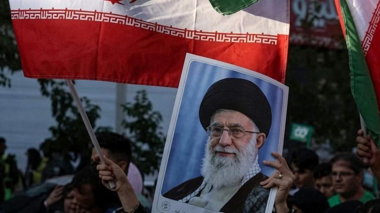 Protester holds poster of Khamenei and Iranian flag.