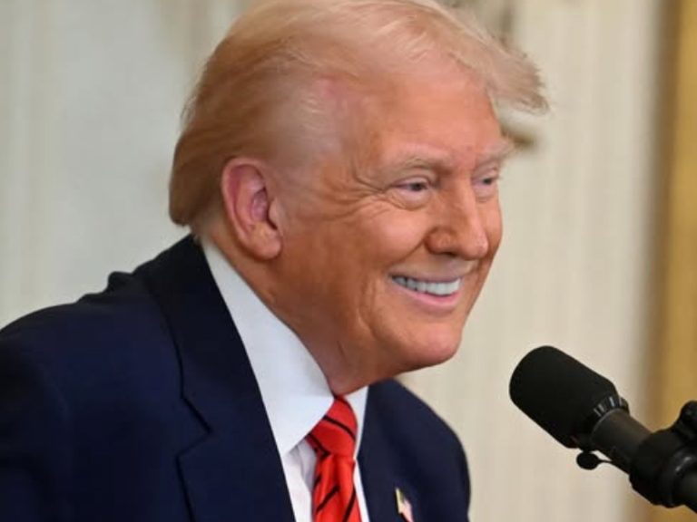 Donald Trump smiling at a microphone.